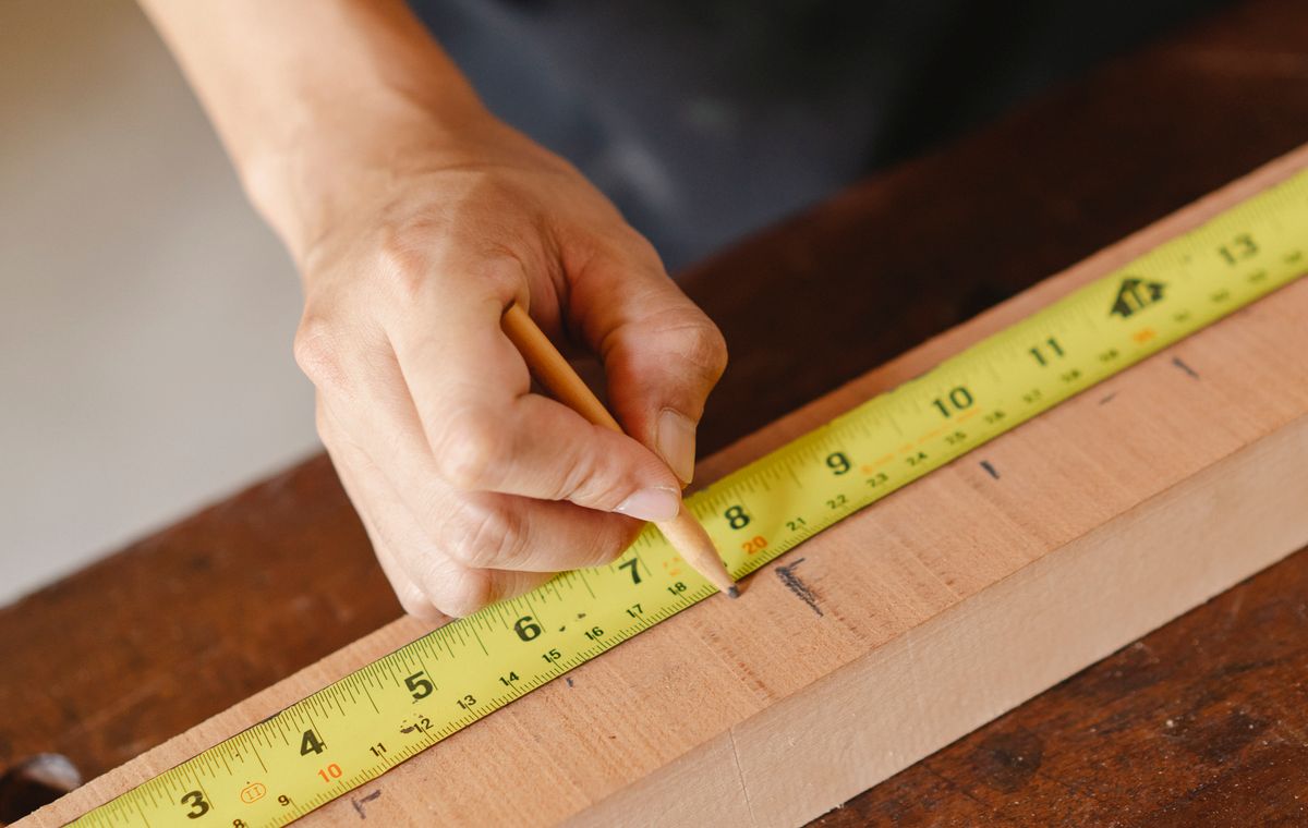 Craftsman measuring and marking a wood board