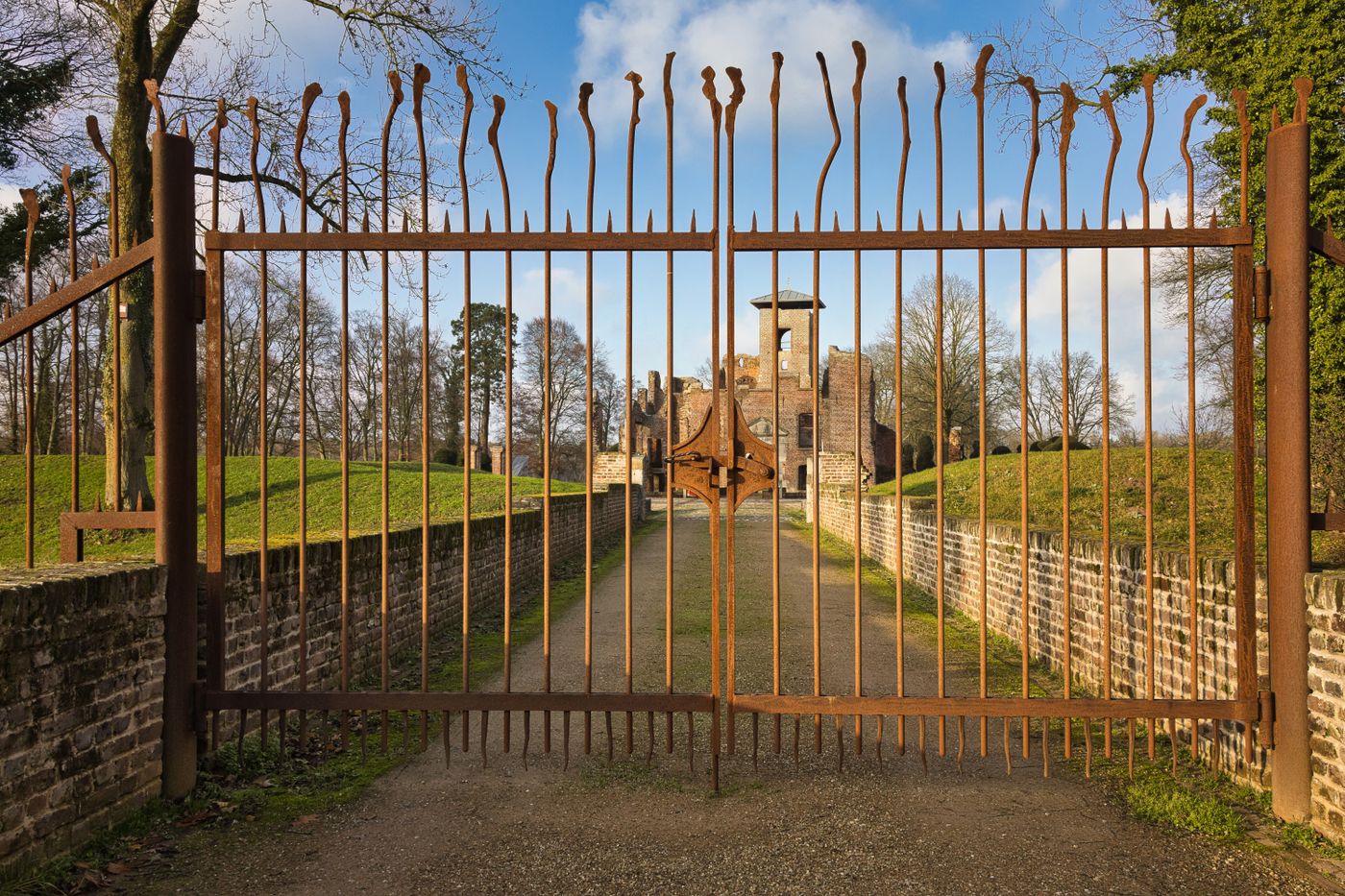 Tall iron estate gate opening onto a long drive